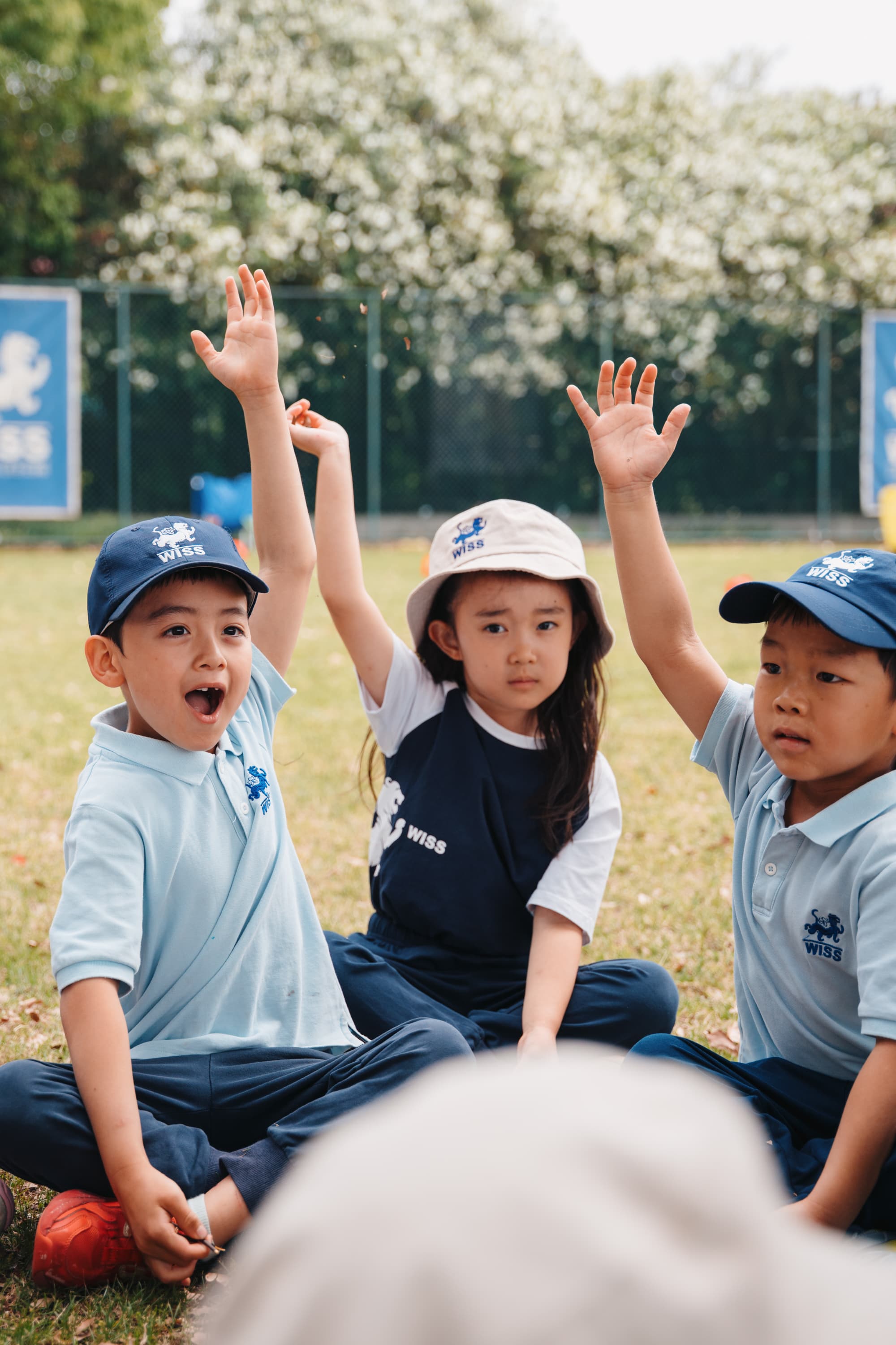 Young students with hands raised during outdoor activity